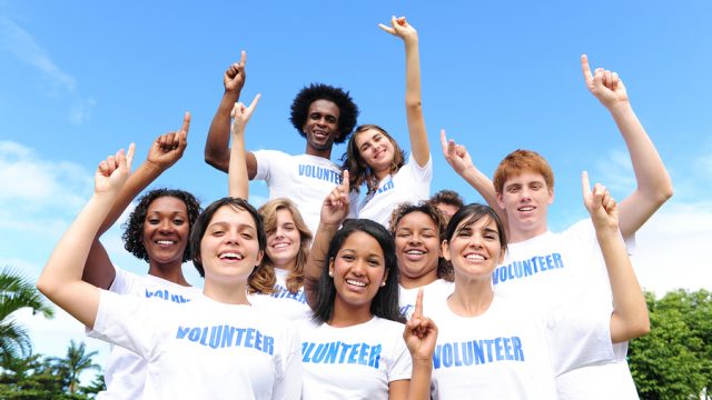 portrait of a happy and diverse volunteer group hands raised